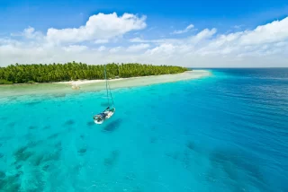 Sailing yacht anchoring in the shallow waters of suwarrow atoll, cook islands, polynesia, pacific ocean